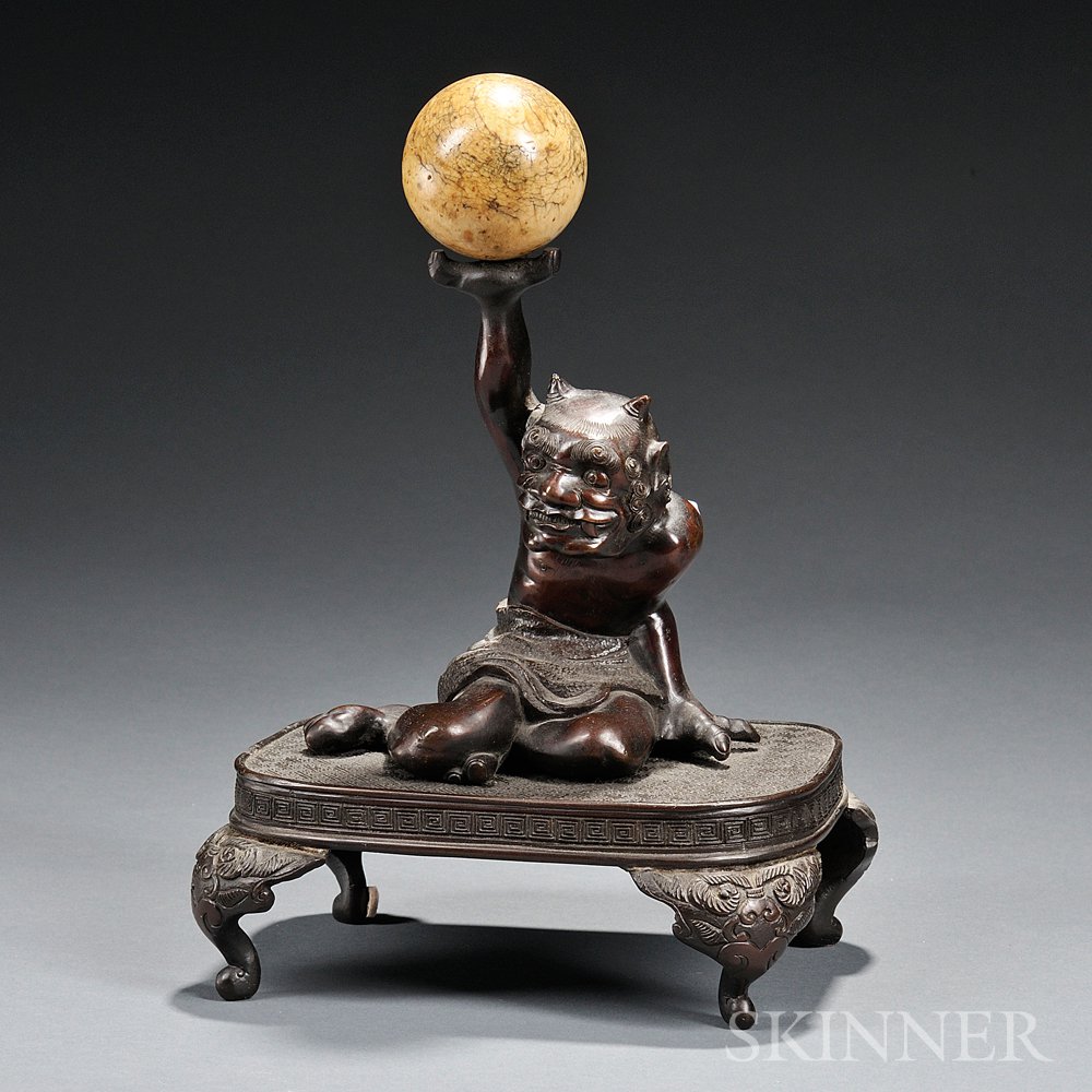 Appraisal: Bronze Oni Japan seated on a table holding a ball