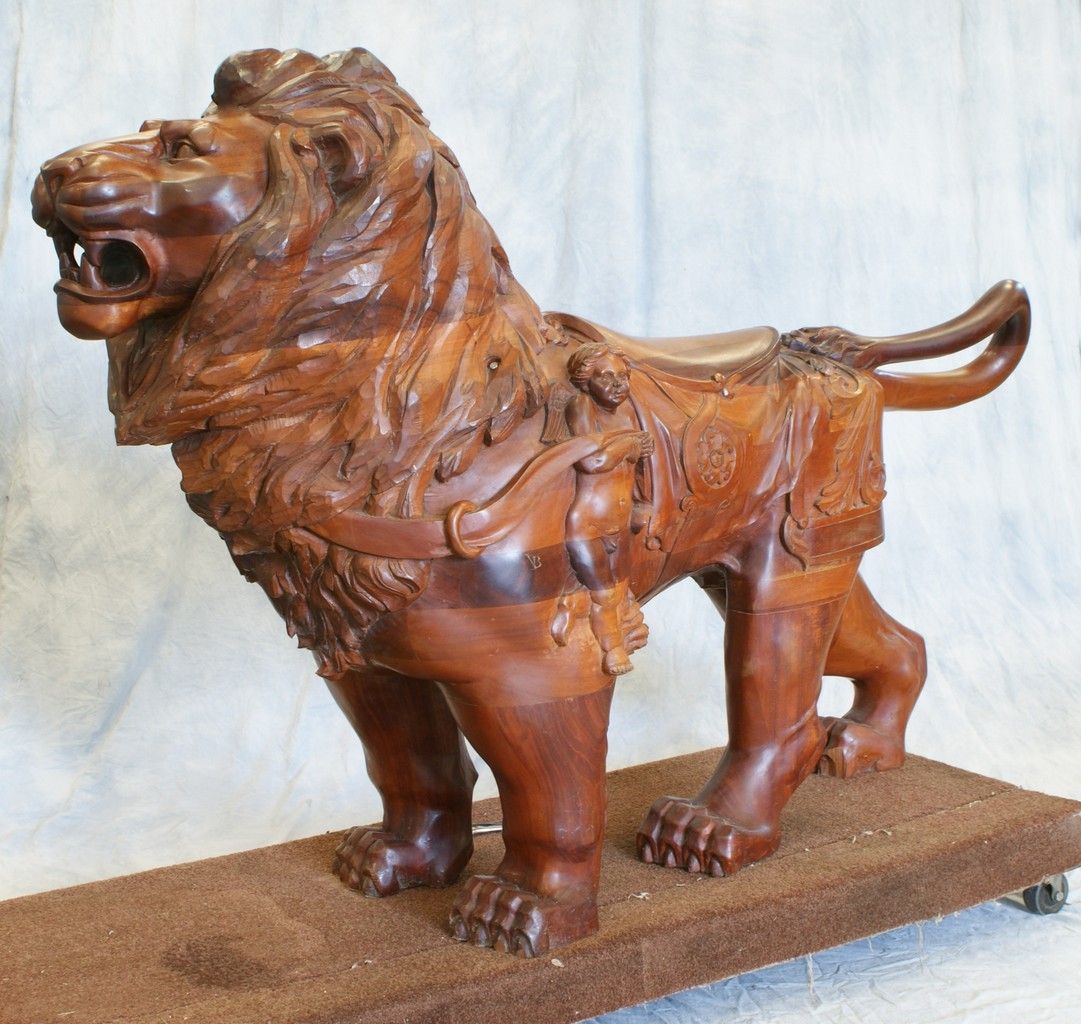 Appraisal: Carved mahogany standing lion with cherubs flanking saddle late c