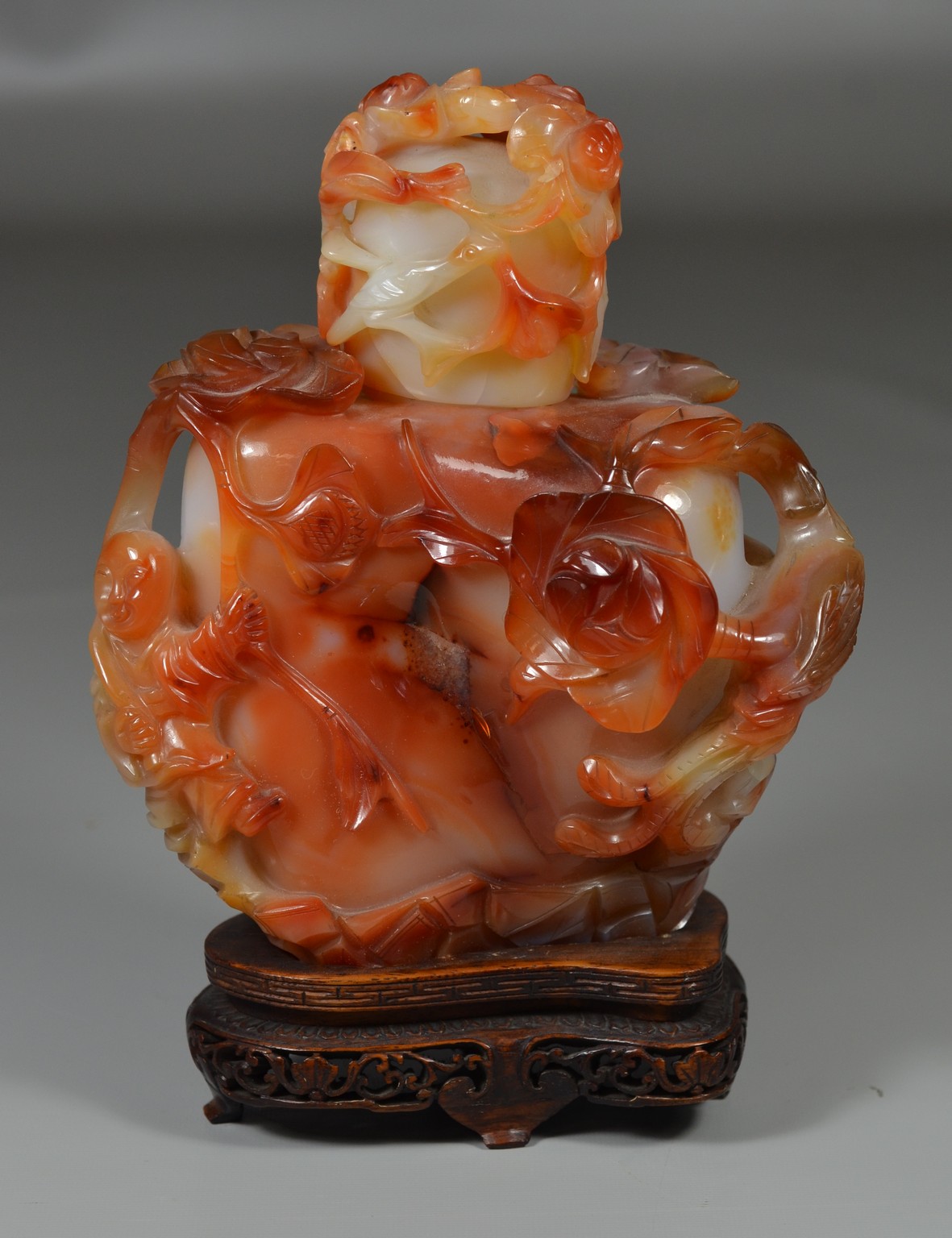 Appraisal: Carved Carnelian vessel with lid on hardwood base figure flowers