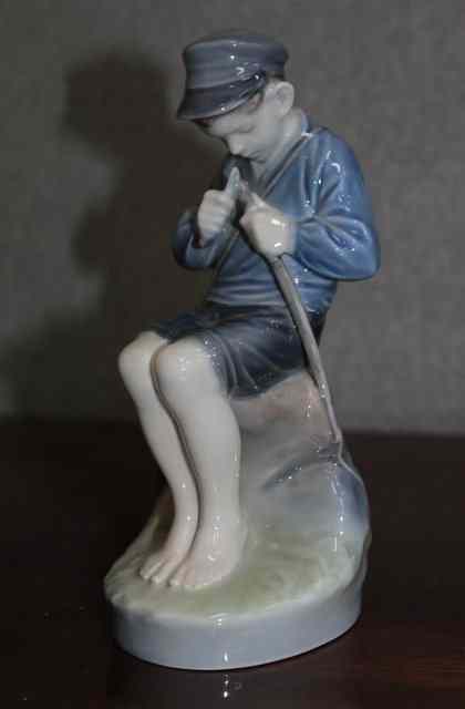 Appraisal: A ROYAL COPENHAGEN FIGURE of a boy whittling a stick