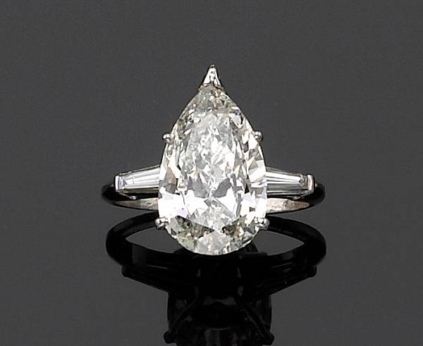 Appraisal: A diamond and platinum ring centering a pear-shaped diamond flanked