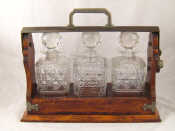 Appraisal: A three bottle oak framed tantalus with three cut glass