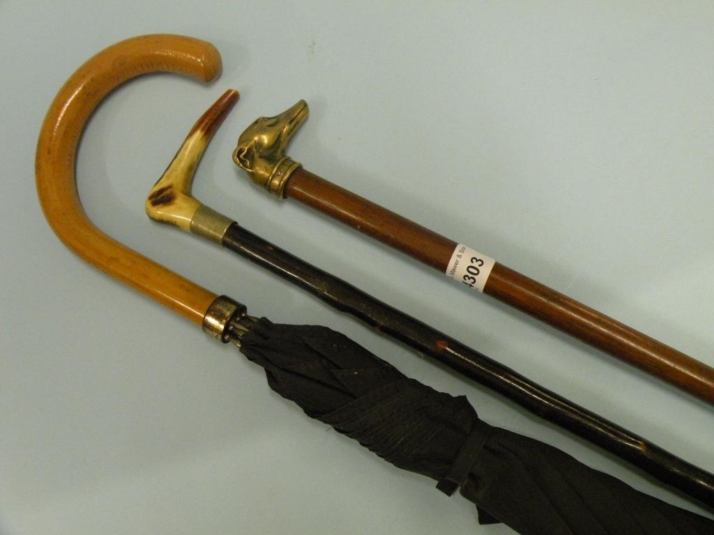 Appraisal: A mahogany walking stick with a brass handle cast in