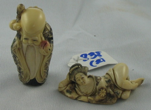 Appraisal: TWO IVORY NETSUKE the first a reclining female figure in