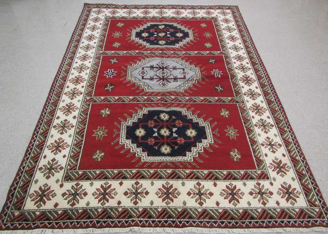 Appraisal: HAND KNOTTED ORIENTAL CARPET three geometric medallion design on red