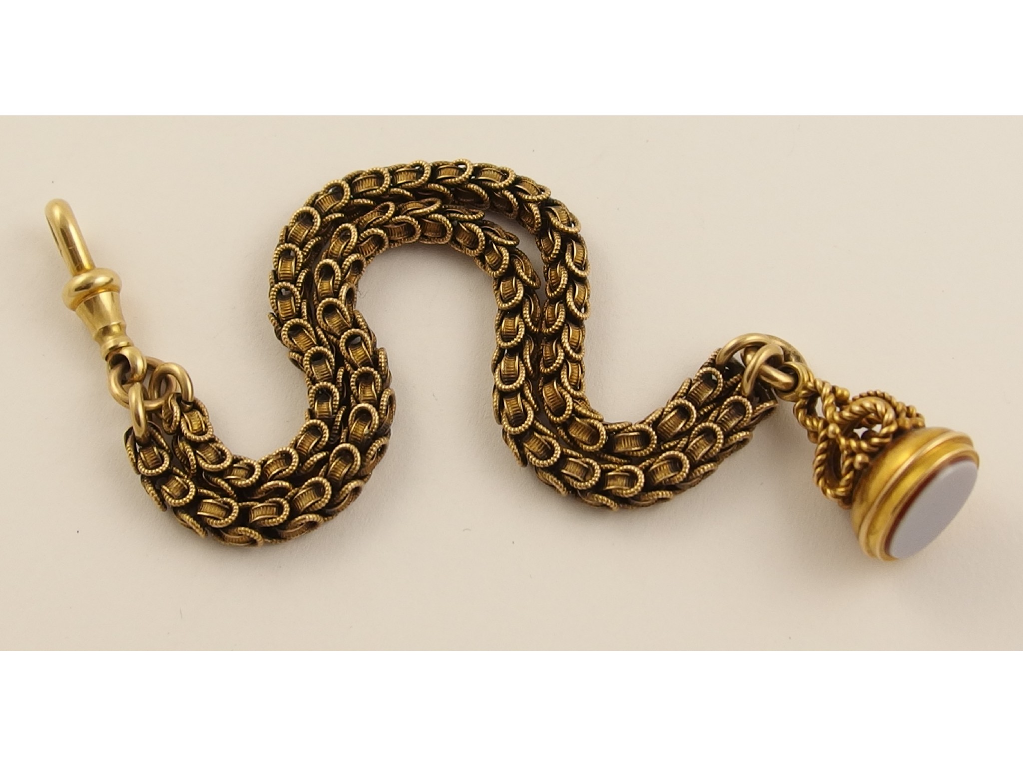 Appraisal: A yellow metal Albert chain with decorative links and a