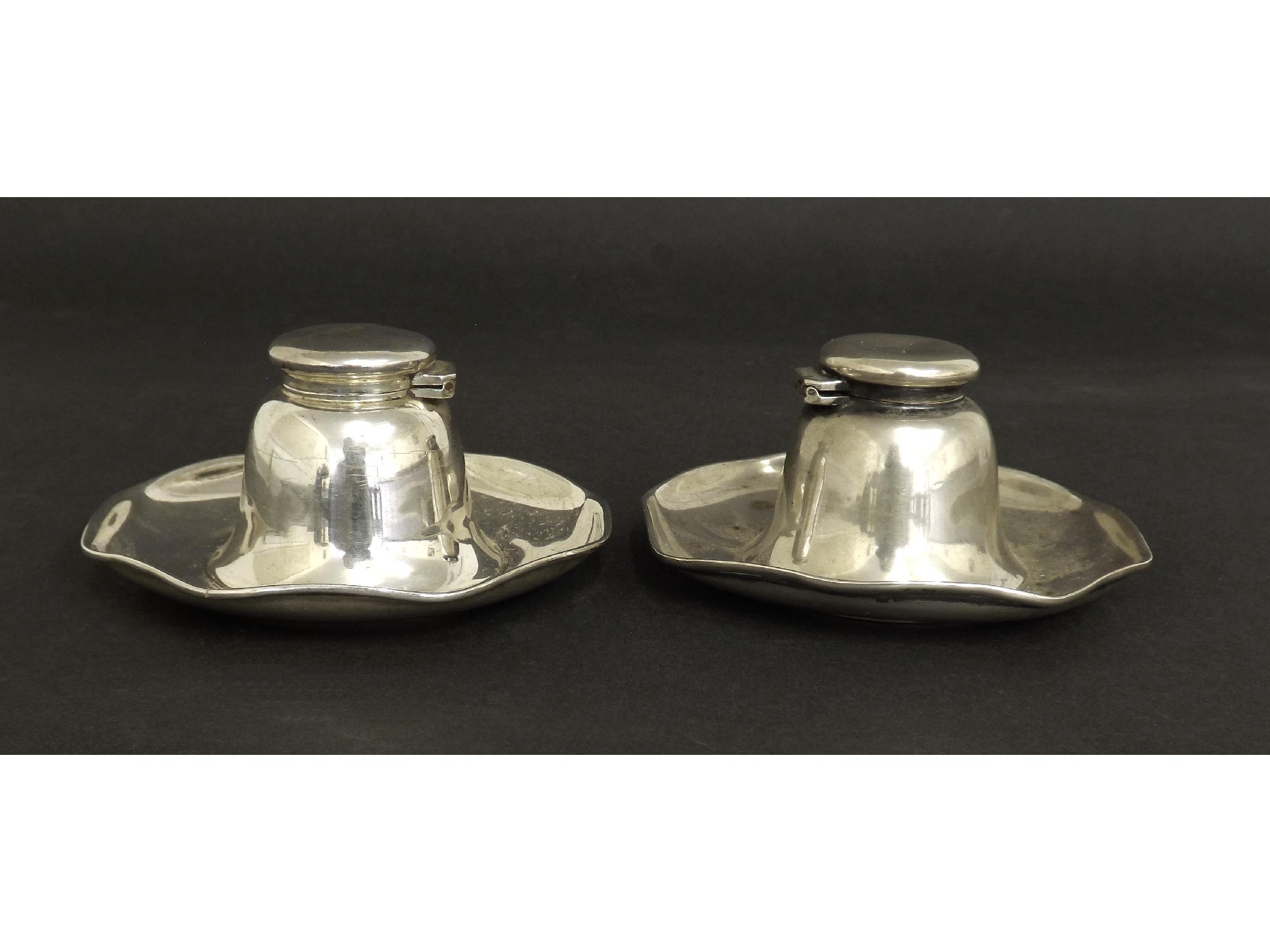 Appraisal: Pair of Edwardian silver capstan inkwells upon wavy dishes maker