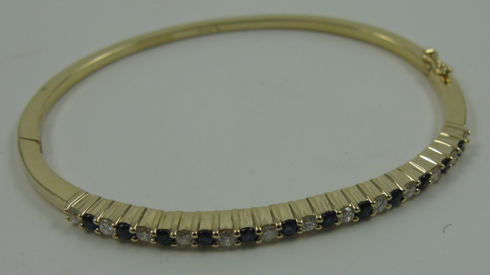 Appraisal: SAPPHIRE DIAMOND AND FOURTEEN KARAT GOLD BANGLE set with round-cut