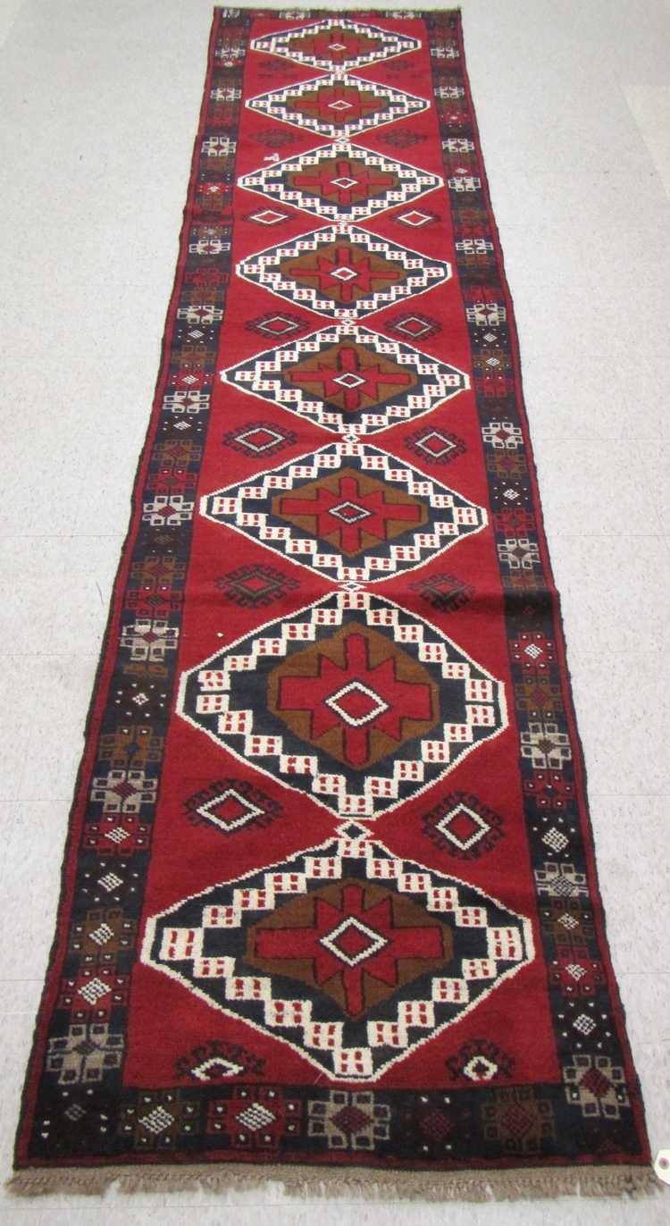 Appraisal: HAND KNOTTED ORIENTAL RUNNER Pakistani Belouch featuring a column of