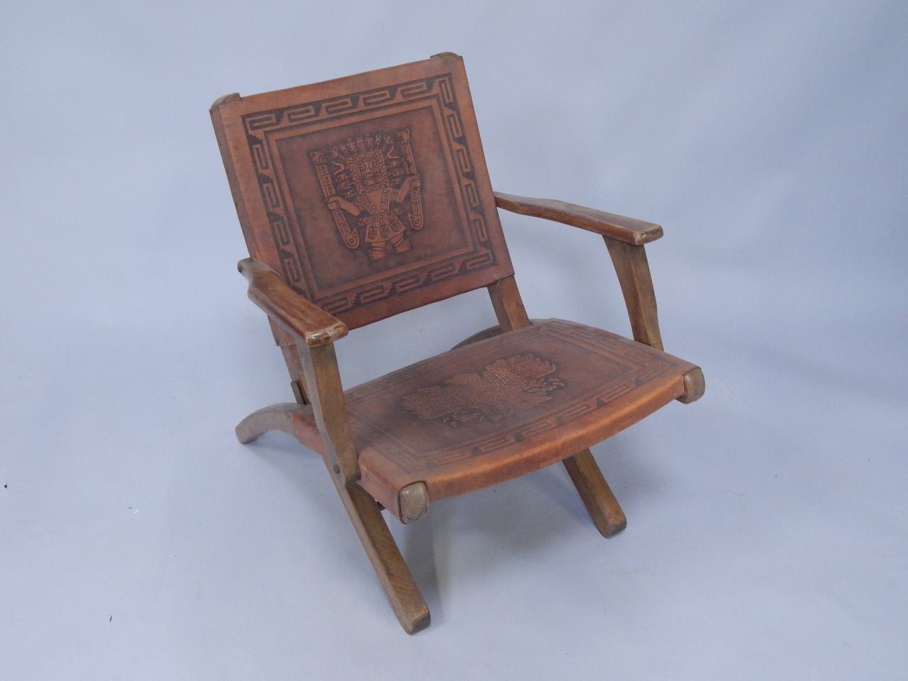 Appraisal: A hardwood folding armchair with embossed leather back and seat