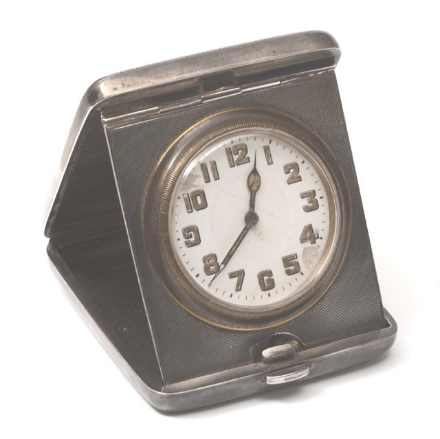 Appraisal: A WHITE METAL TRAVELLING CLOCK with silver plated timepiece with