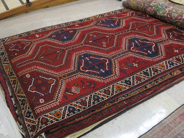 Appraisal: PERSIAN SHIRAZ CARPET featuring three columns of geometric medallions on