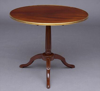 Appraisal: LOUIS XVI-STYLE MAHOGANY CIRCULAR TRIPOD TABLE The circular brass-bound mahogany