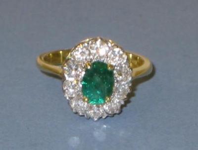 Appraisal: AN EMERALD AND DIAMOND CLUSTER RING the oval cut emerald