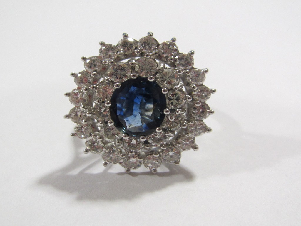 Appraisal: An eighteen carat white gold sapphire and diamond cluster ring