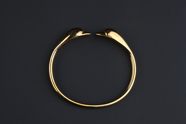 Appraisal: A DOLPHIN BANGLE of torque design with dolphin's head terminals