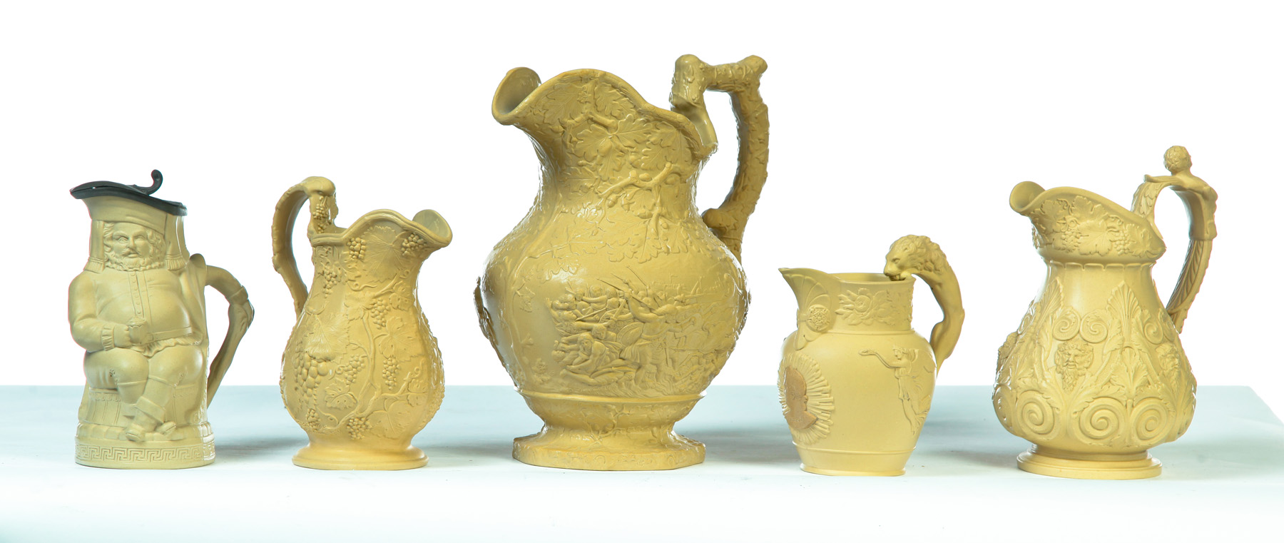 Appraisal: FIVE RELIEF MOLDED SCENIC TAN PITCHERS England mid th century