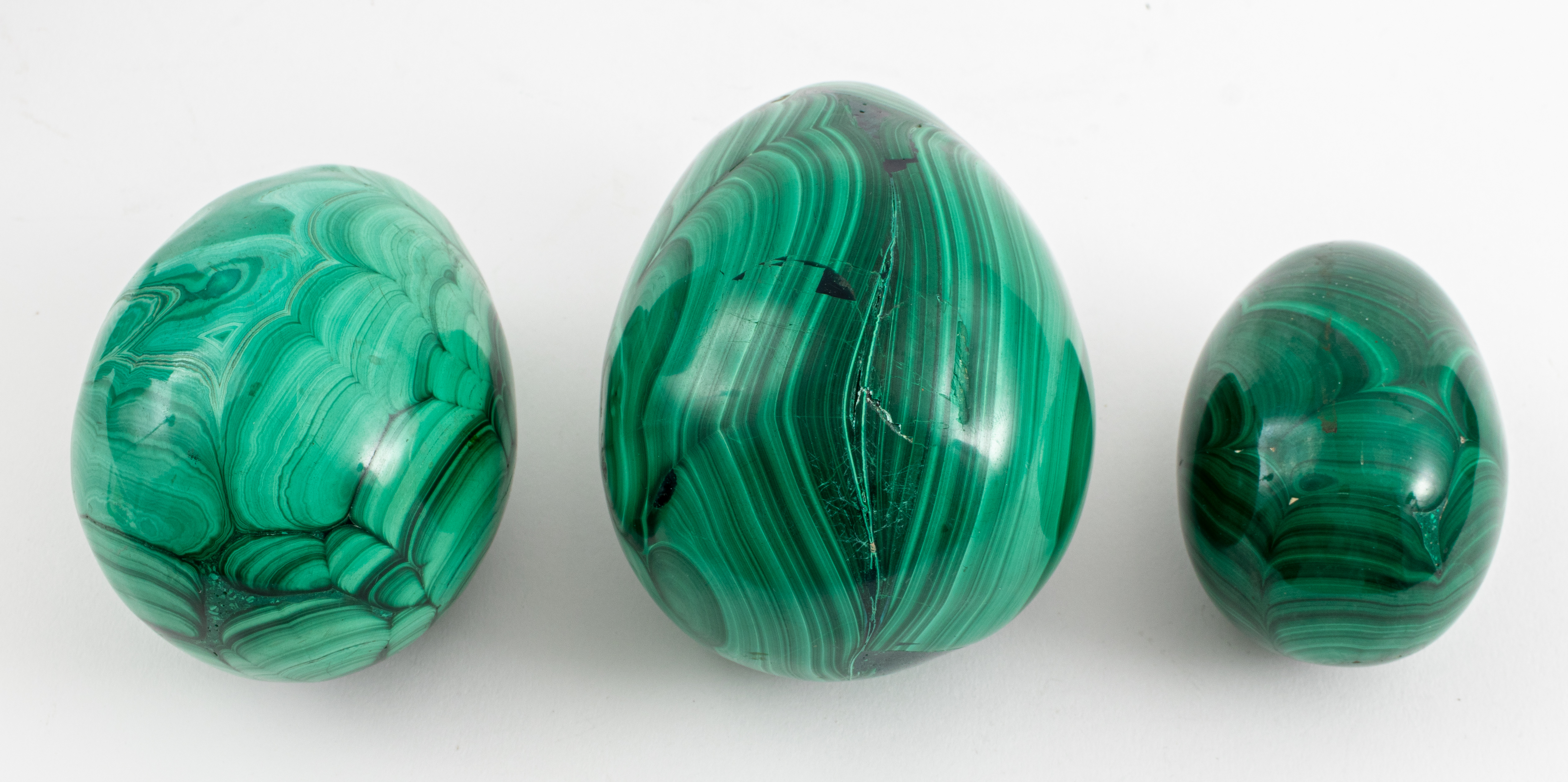 Appraisal: MALACHITE EGGS Three malachite mineral specimens carved into egg shapes