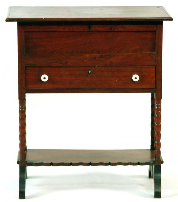 Appraisal: A walnut lift-top sewing box resting upon four turned feet