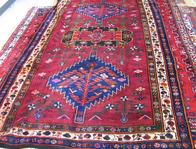 Appraisal: PERSIAN TRIBAL CARPET three geometric medallion design on burgundy ground