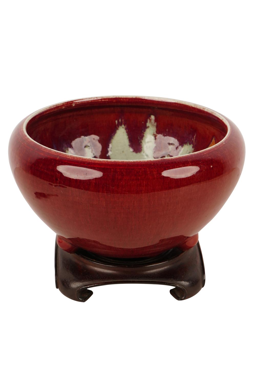 Appraisal: CHINESE OXBLOOD CERAMIC THREE LEGGED JARon an undersized wood base