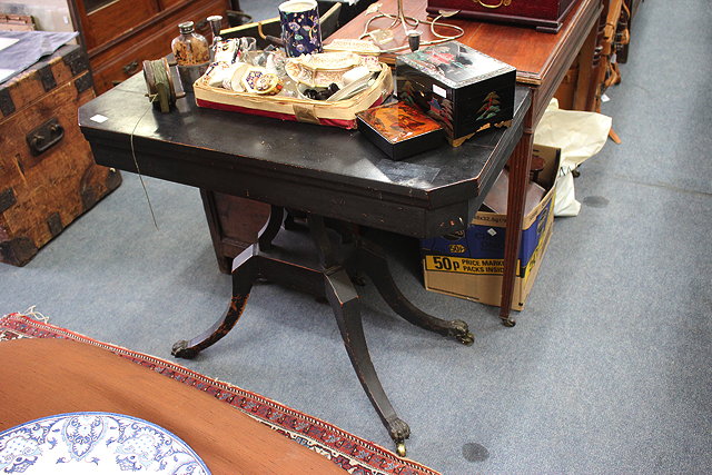 Appraisal: A VICTORIAN EBONISED FOLD OVER CARD TABLE with canted front