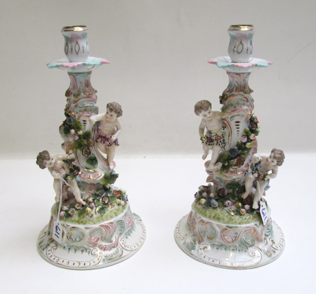 Appraisal: PAIR OF GERMAN PORCELAIN FIGURAL CANDLESTICKS featuring painted flowers putti