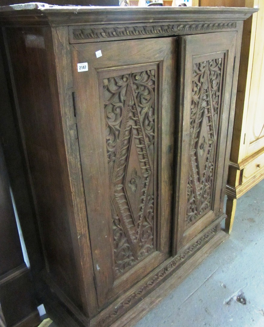 Appraisal: A hardwood two door cupboard with carved panels