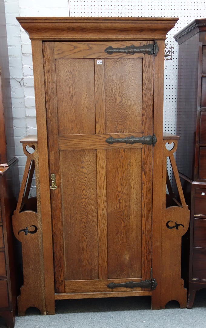 Appraisal: An Art Nouveau oak hall cupboard with panel door flanked