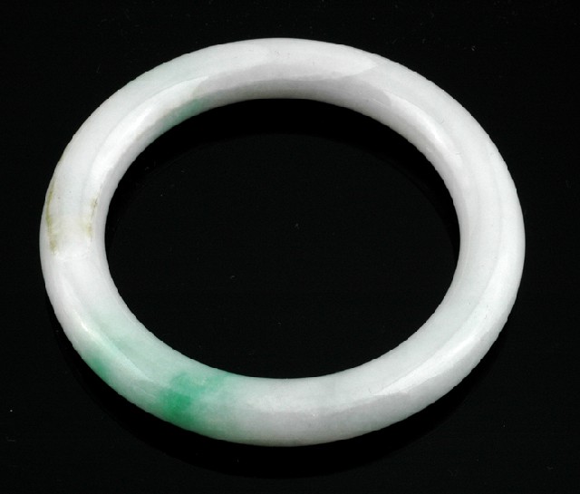 Appraisal: A JADEITE BANGLE The round bangle of mottled pale green