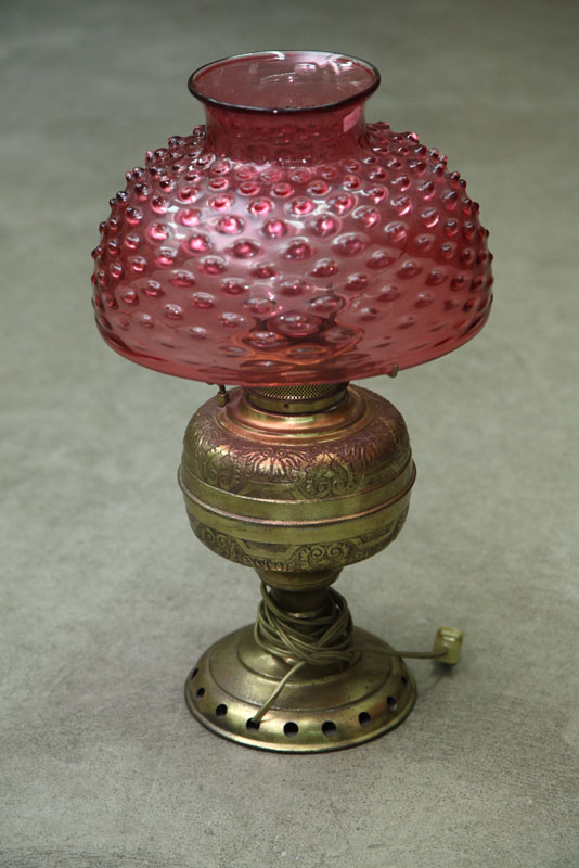 Appraisal: KEROSENE LAMP Brass embossed Rochester type base with a cranberry