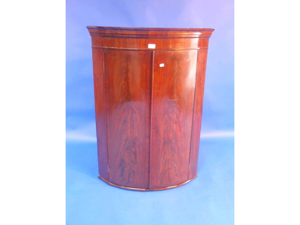 Appraisal: A George III flamed mahogany bow front hanging corner cupboard