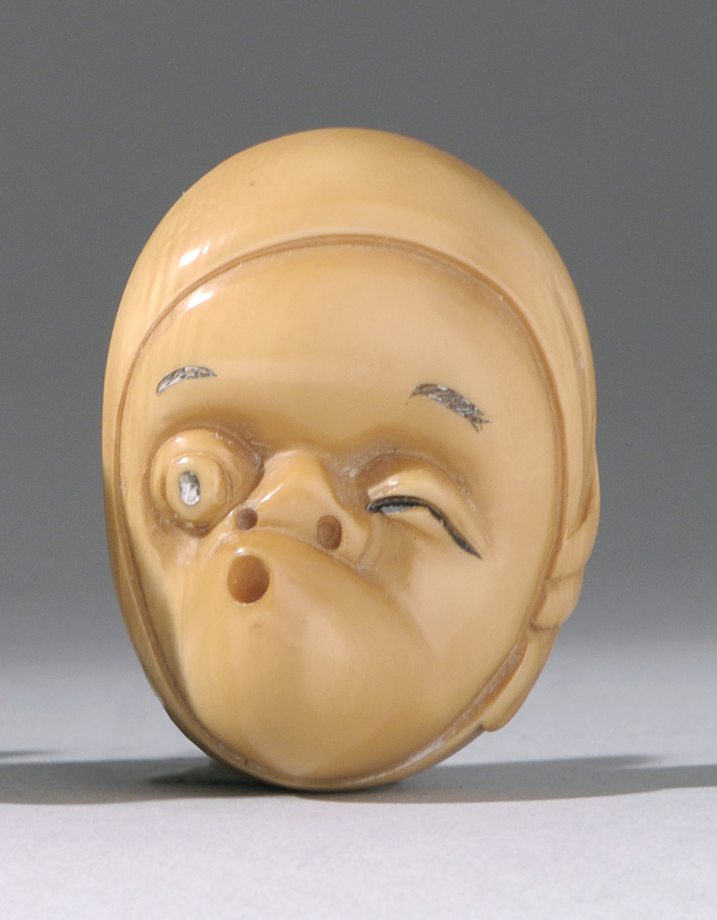 Appraisal: CARVED TAGUA NUT NETSUKE Early th CenturyThe face of an