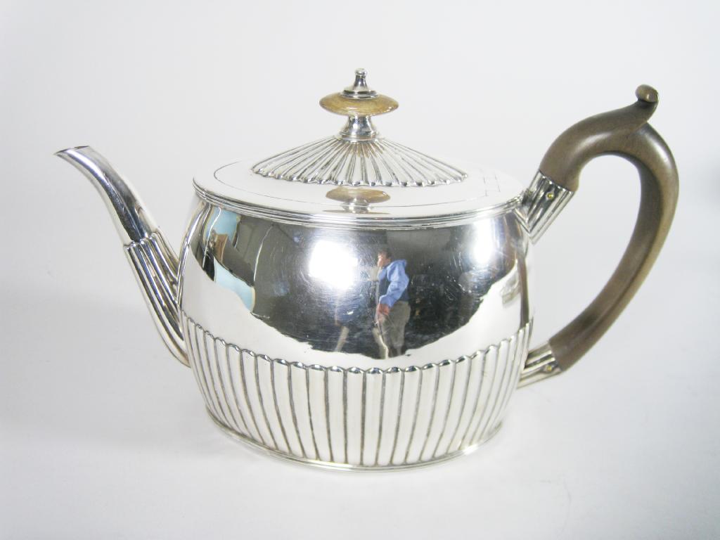 Appraisal: A George III oval semi-fluted Teapot with wooden scroll handle