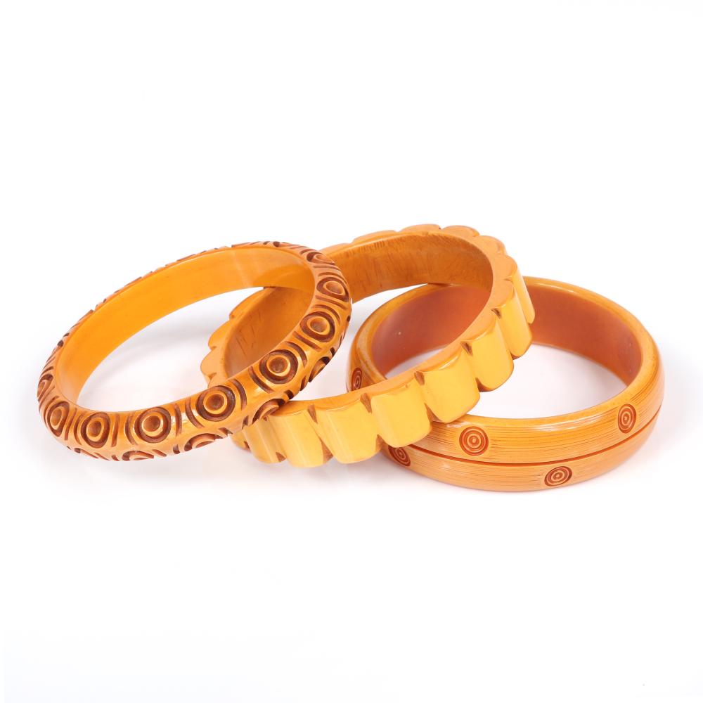 Appraisal: THREE CARVED BUTTERSCOTCH BAKELITE BANGLE BRACELETS ONE SCALLOPED AND TWO