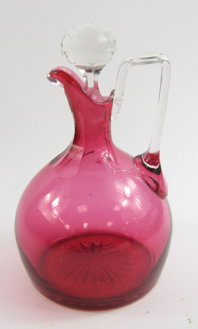 Appraisal: An Edwardian cranberry glass claret jug with a star cut