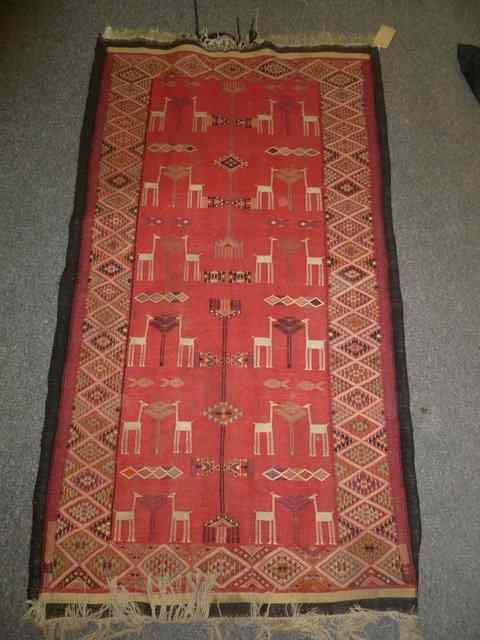 Appraisal: A TRIBAL FLAT WEAVE RED GROUND RUG with central stylised