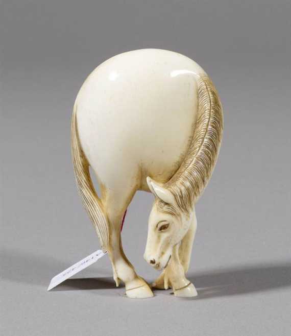 Appraisal: AN IVORY NETSUKE OF A GRAZING HORSE Japan th ct