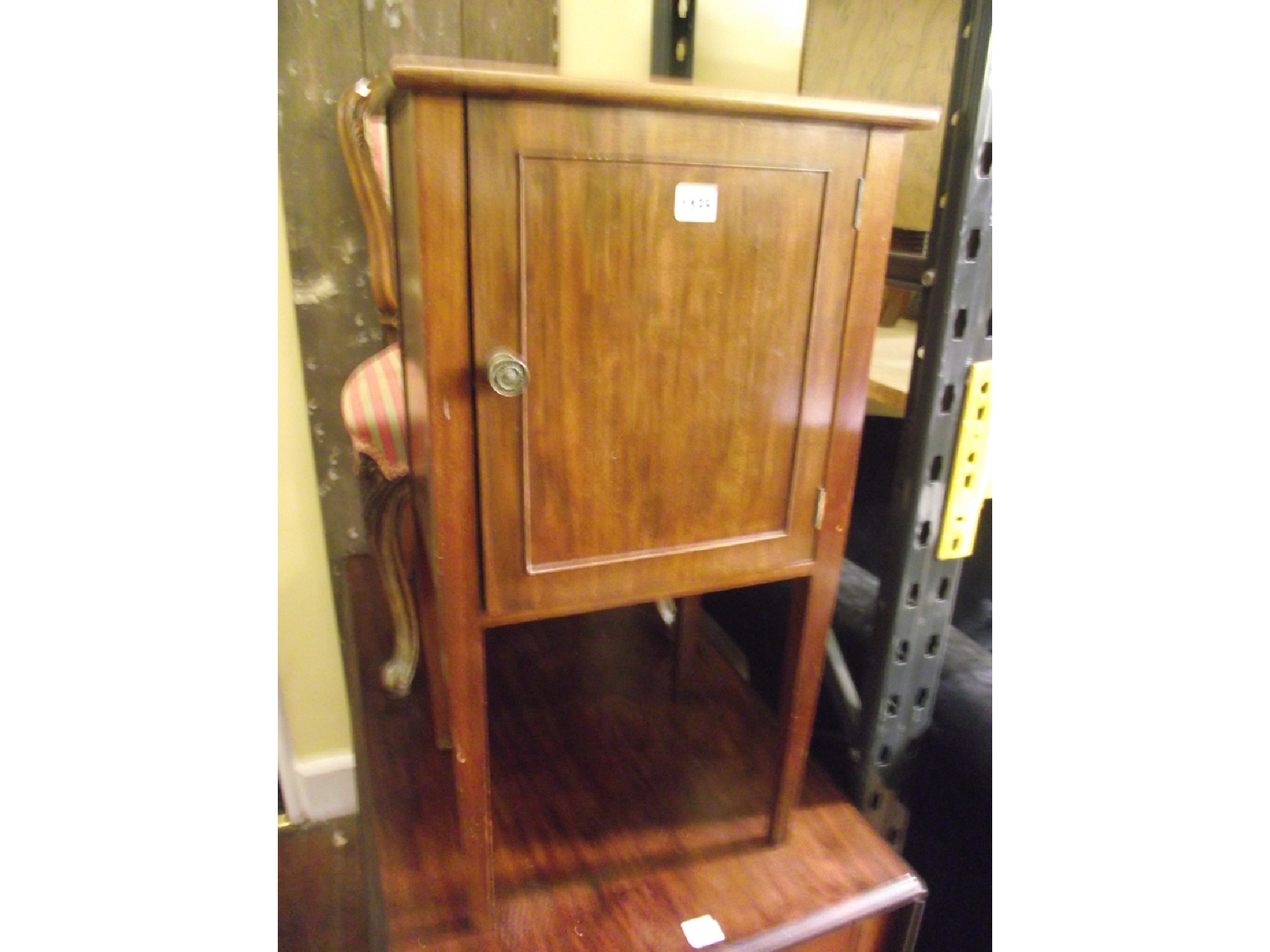 Appraisal: An Edwardian mahogany bedside cupboard enclosed by a panelled door