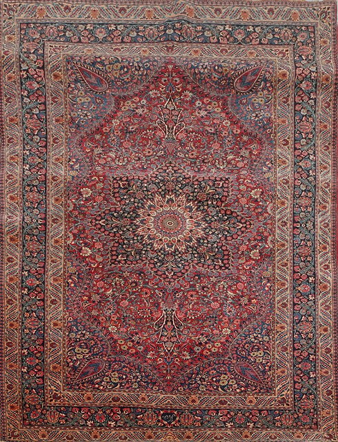 Appraisal: A MASHAD DARK RED GROUND RUG with central radiating medallion