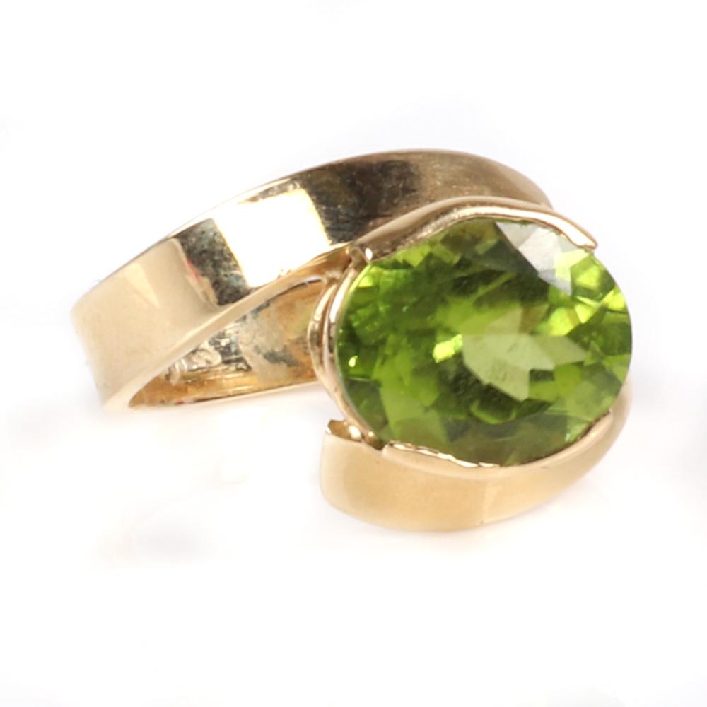 Appraisal: STAMPED K YELLOW GOLD OVAL PERIDOT RING WITH BYPASS DESIGN