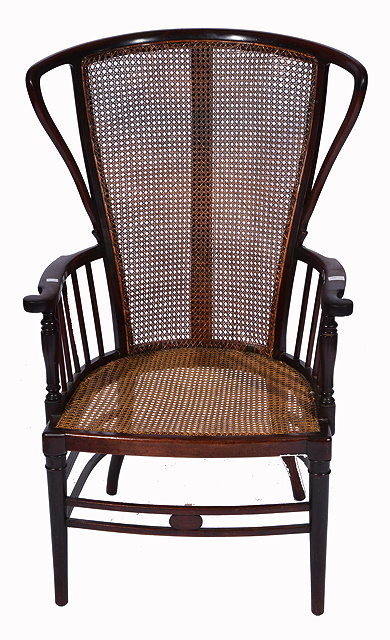 Appraisal: AN EDWARDIAN MAHOGANY WINGED ARMCHAIR with caned back and seat