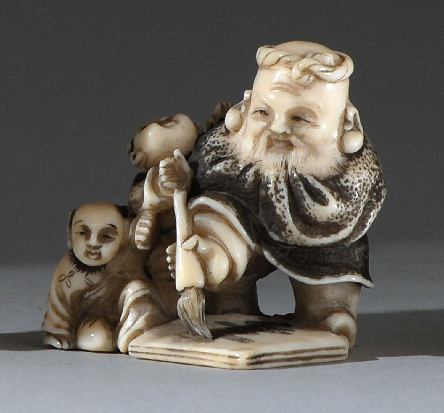 Appraisal: IVORY NETSUKE Taisho PeriodDepicting Fukurokuju and two children painting calligraphy