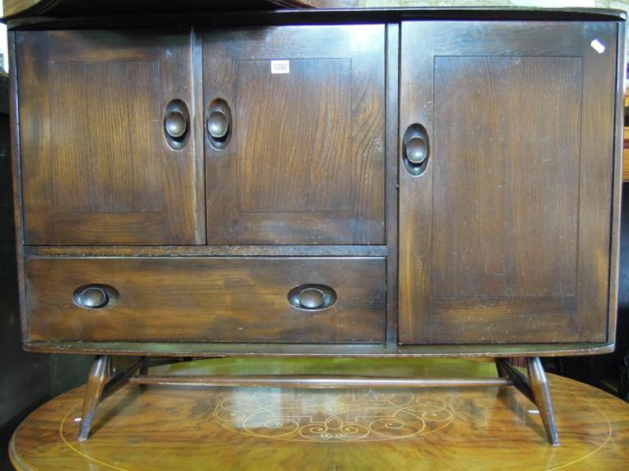 Appraisal: An Ercol dark elm and beechwood sideboard enclosed by three