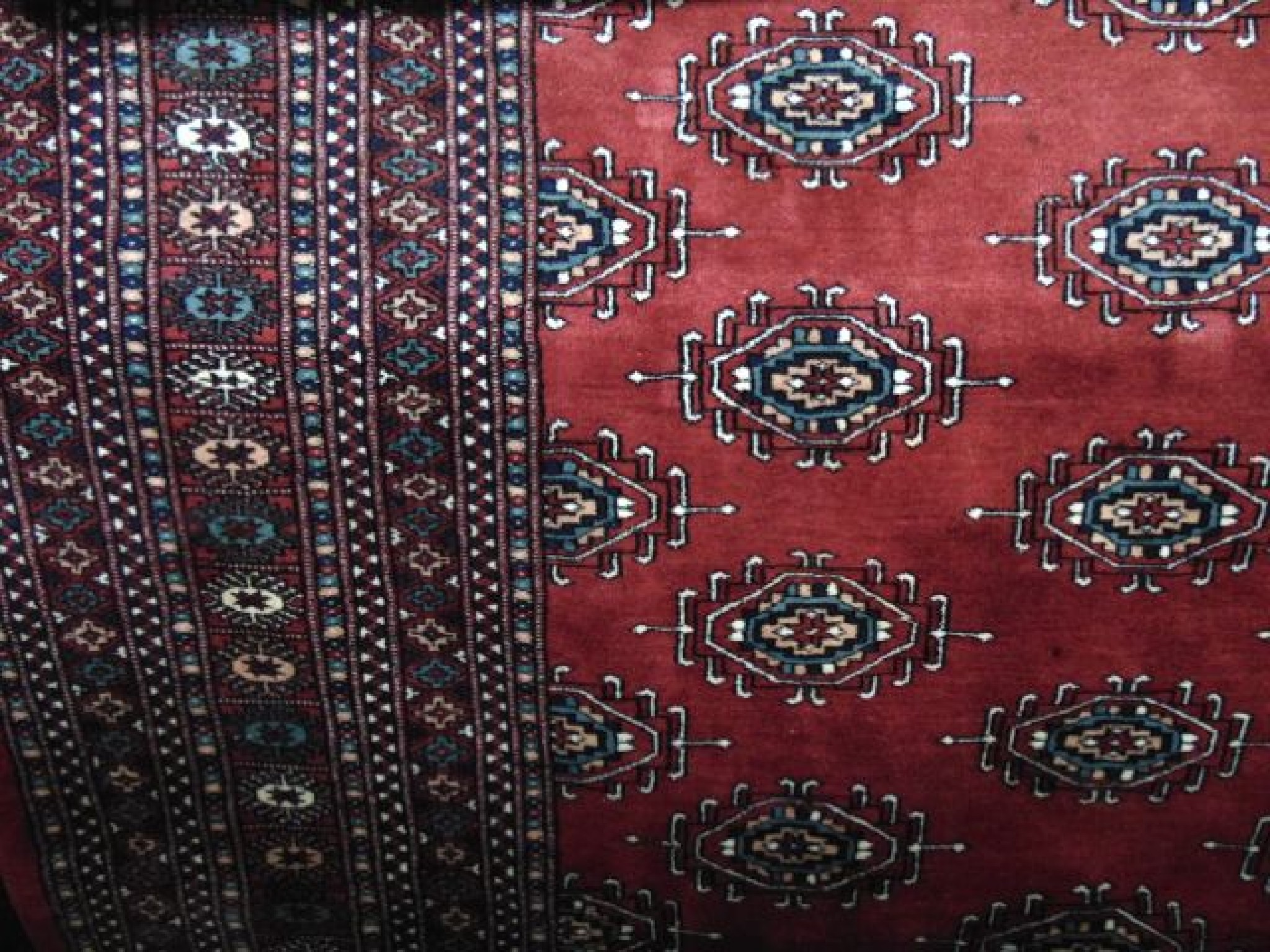 Appraisal: An Afghan red ground wool carpet with multi-medallion centre and