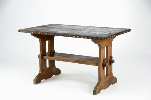 Appraisal: GUSTAV STICKLEY Leather-top trestle table with lower shelf mortised through