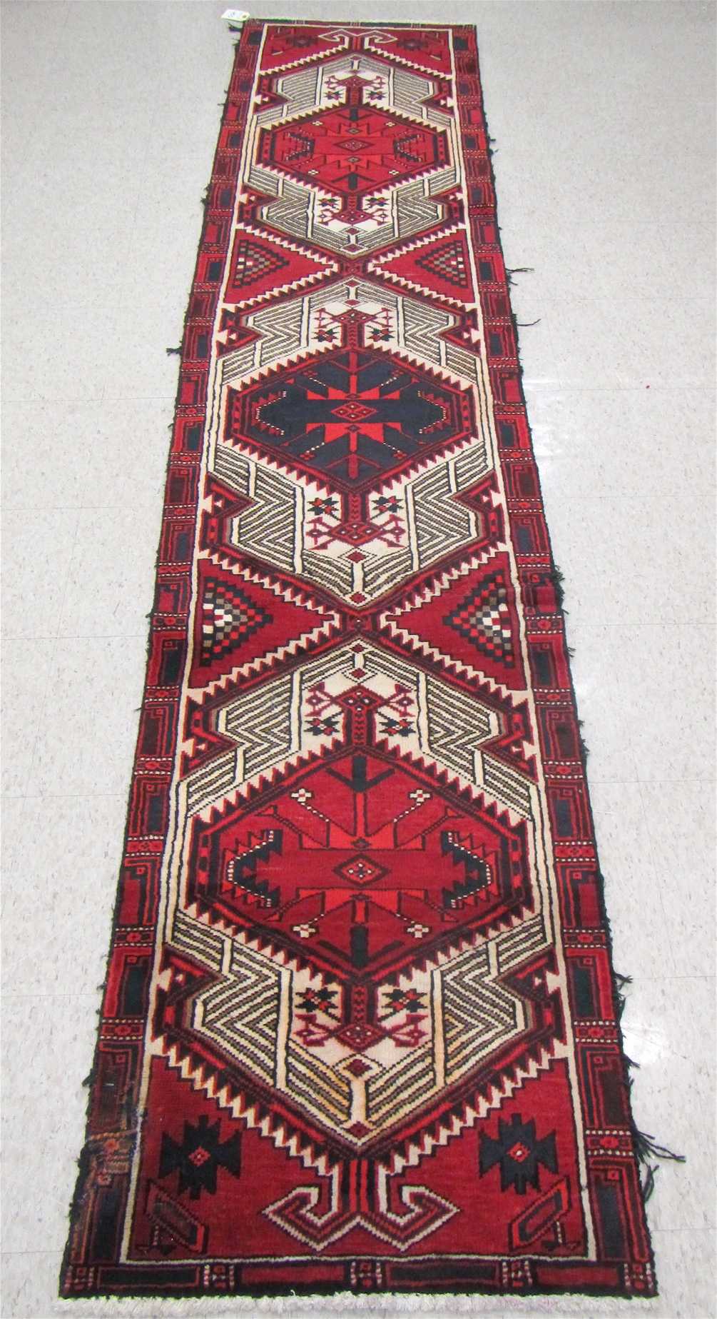 Appraisal: PERSIAN RUNNER repeating geometric medallion design hand knotted ' x