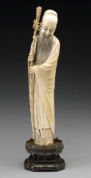 Appraisal: A tinted ivory figure of a standing Daoist immortal holding