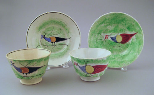 Appraisal: Two green spatter cups and saucers th c with peafowl