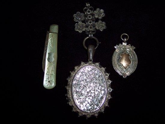 Appraisal: An oval silver locket with engraved foliate decoration to a